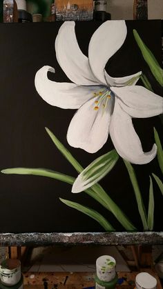 a painting of white flowers on a black background with paintbrushes in the foreground