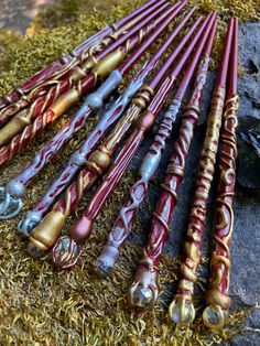 several red and gold colored sticks laying on top of some green grass next to a rock