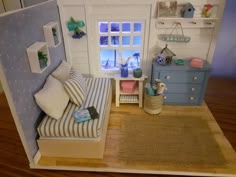 a doll house with a bed, dresser and window in the corner that is open