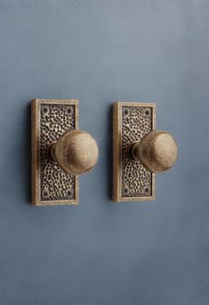 two metal knobs on the side of a wall with blue walls in the background