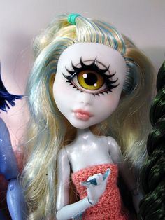 a close up of a doll with long blonde hair and big eyes wearing a dress