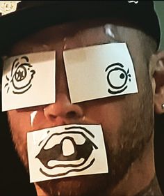 a man with paper taped to his face has eyes drawn on the side of his face