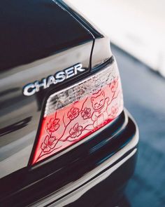 the rear end of a black car with red stickers on it's bumper