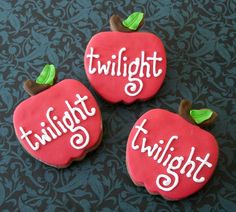 three decorated cookies with the words twilight and an apple on them are sitting next to each other