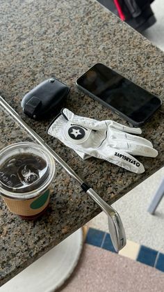 a table topped with a cup of coffee next to a cell phone and other items