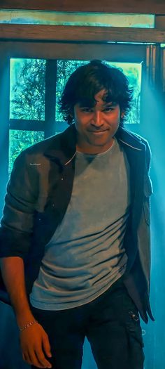 a man standing in front of a window with blue light coming from behind his back