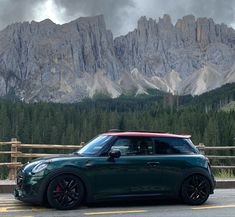 a green mini cooper parked in front of mountains