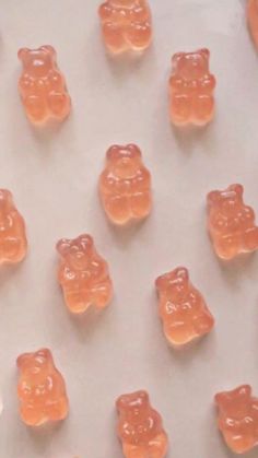 there are many small gummy bears on the table together, and one is orange