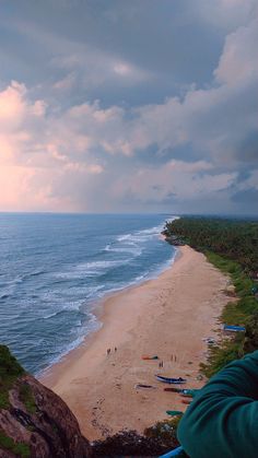 a person taking a photo of the beach and ocean from a high viewpoint point on a cloudy day