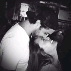 a man and woman kissing each other in front of a bar