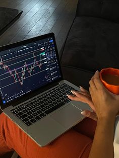 a woman is sitting on the couch with her laptop and coffee cup in front of her