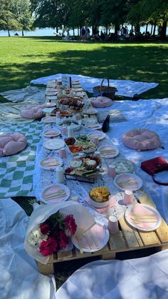 an outdoor picnic is set up with plates and food on the table for people to eat