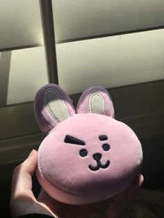 a person is holding a pink stuffed animal with ears on it's head and nose