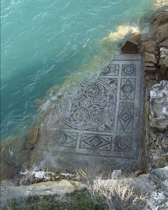 an artistic painting on the side of a cliff next to water