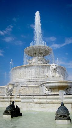 a fountain with water spouting from it's sides in front of a blue sky
