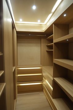 an empty walk - in closet with wooden shelves and lights on the ceiling is lit by recessed lighting
