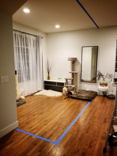 an empty living room with hardwood floors and cat furniture on the floor in front of a window