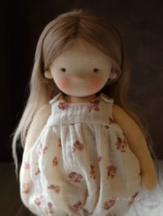 the doll is wearing a white dress with red flowers on it's chest and legs