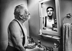 an old man standing in front of a bathroom sink looking at himself in the mirror
