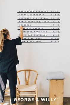 a woman standing in front of a white wall with writing on it that reads, george & willy