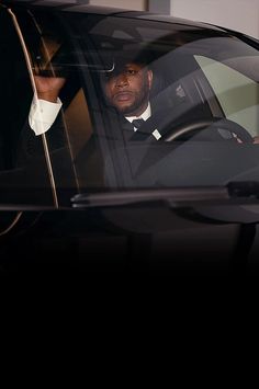 a man in a tuxedo is sitting in the driver's seat of a car
