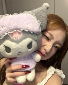 a woman holding a gray and white stuffed animal