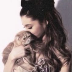 a woman holding a cat in her hands and wearing a bow on top of it
