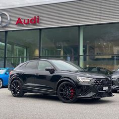 audi cars are parked in front of a dealership with their logo on the building