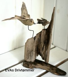 two birds are standing on top of a piece of wood that has been carved into the shape of a bird