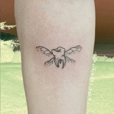 a small tattoo on the leg of a woman with a bird flying above her head