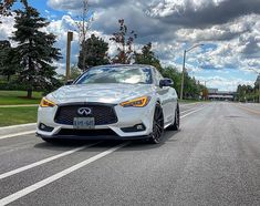 a white car is parked on the side of the road in front of some trees