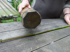 a person holding a piece of wood on top of a wooden table