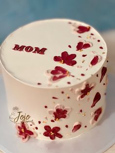 a white cake with red flowers and the word mom on top is sitting on a plate