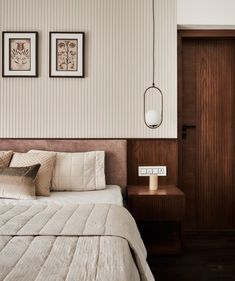 a bed with two pictures on the wall above it and a night stand next to it