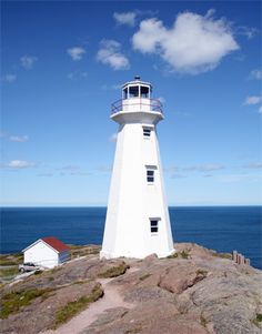 a white lighthouse sitting on top of a rocky cliff