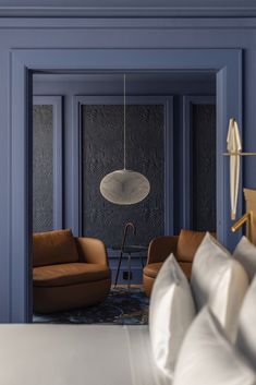 a bedroom with blue walls and furniture in the corner, along with a lamp hanging from the ceiling