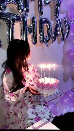 a woman sitting in front of a birthday cake