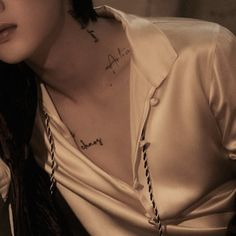 a man with tattoos on his neck and chest sitting next to a woman wearing a white shirt