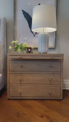 a white lamp sitting on top of a wooden dresser