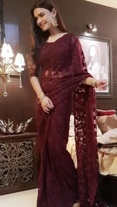 a woman in a maroon sari posing for the camera with her hand on her hip