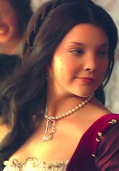 a woman in a red and white dress with pearls on her neck is smiling at the camera