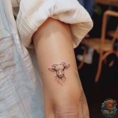 a small sheep tattoo on the arm