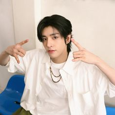 a young man in white shirt pointing to his left side with both hands and fingers