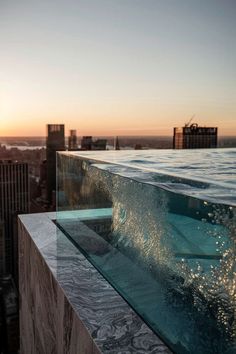 the sun is setting over an ocean with buildings in the background and water below it