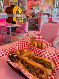 two baskets filled with hot dogs covered in toppings on top of a pink table