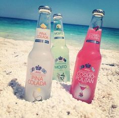 three bottles of water sitting on top of a sandy beach