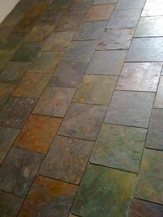 the floor is made out of multicolored slate tiles and has a white wall behind it