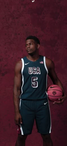 a man holding a basketball while standing in front of a red wall with the words usa on it