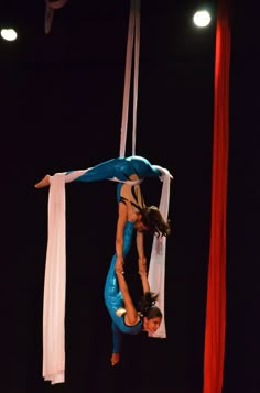two acrobats performing aerial tricks in the air