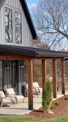 an outside view of a house with chairs on the porch and trees in the background